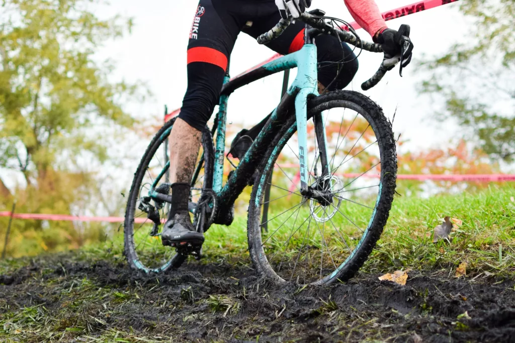 a person riding a cyclocross bike on a muddy trail
