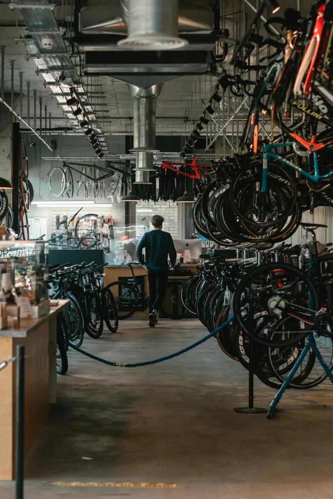 man in black t-shirt standing near black and red bicycle hanging bike in a garage
