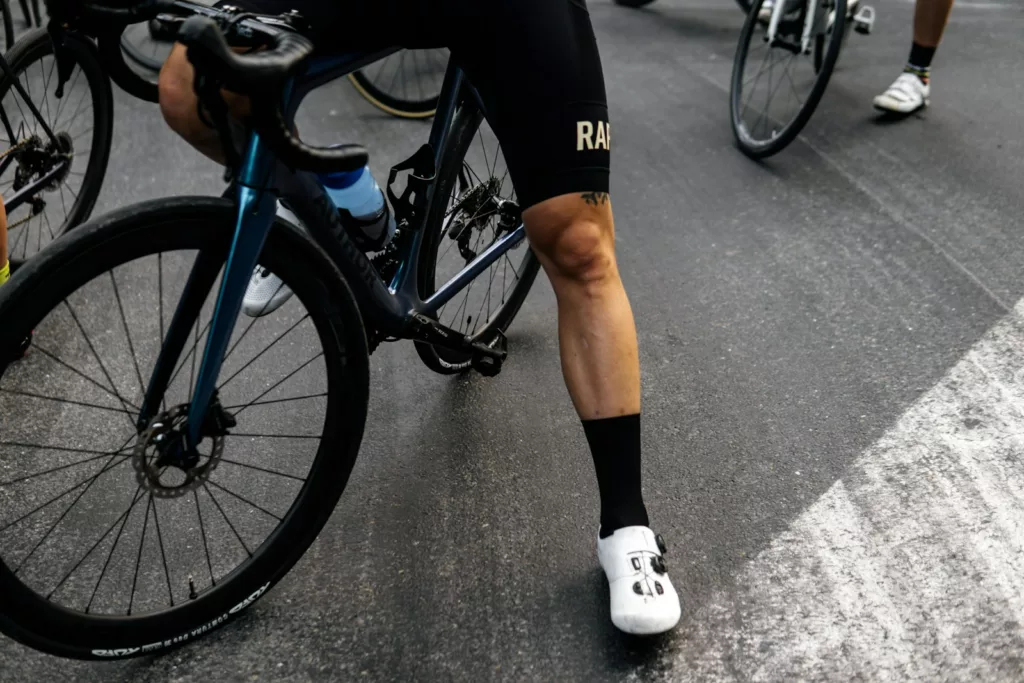person in black shorts and white socks riding blue and black road bike rapha