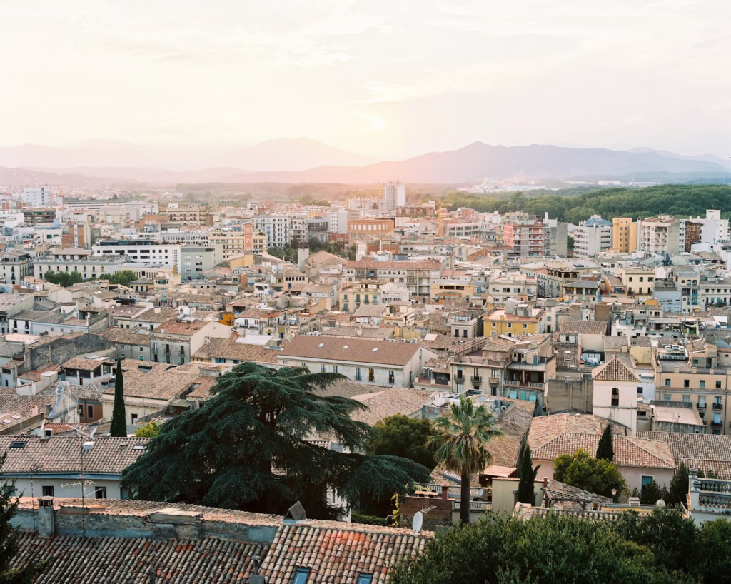 city buildings with brown tiled roofs under grey sky Girona