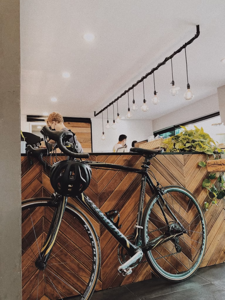 woman in black jacket standing beside blue bicycle