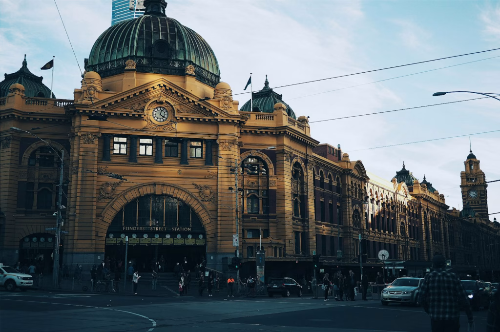 brown building with cars passing infront Melbourne Flinders Street