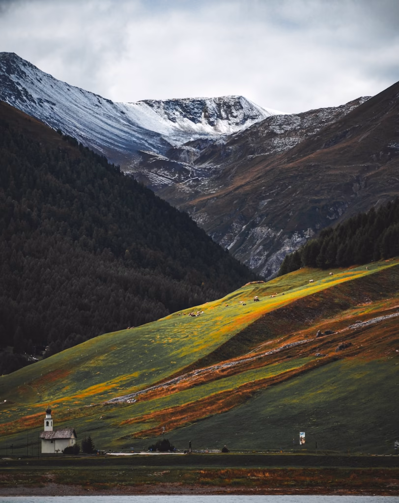 Mountains rise above a quaint church and lush hillside.