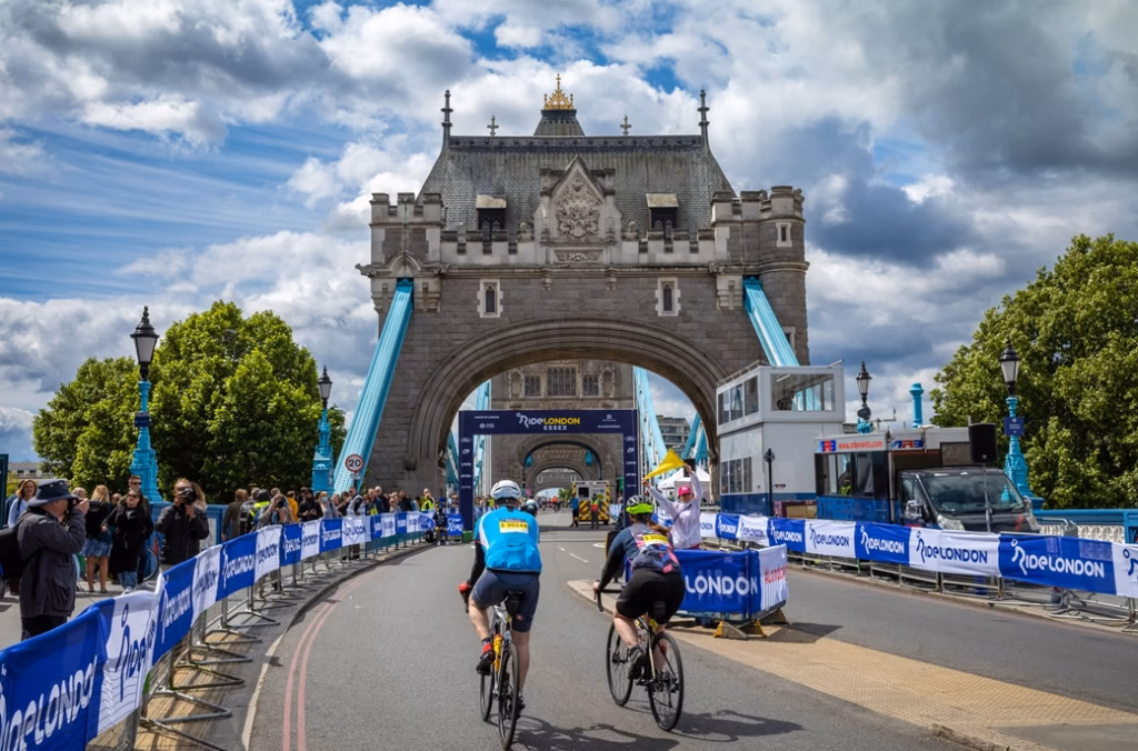 Two male cyclists participating in RideLondon 2022 approach the finish line on Tower Bridge in London.