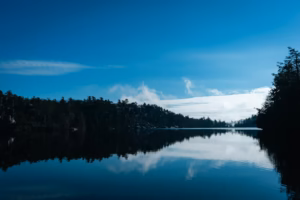Hudson Valley a body of water surrounded by forest under a blue sky
