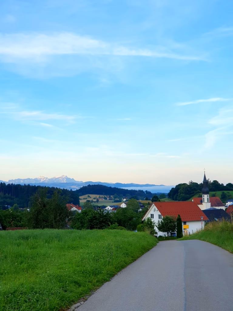 Bavaria Alps A road that is next to a lush green field