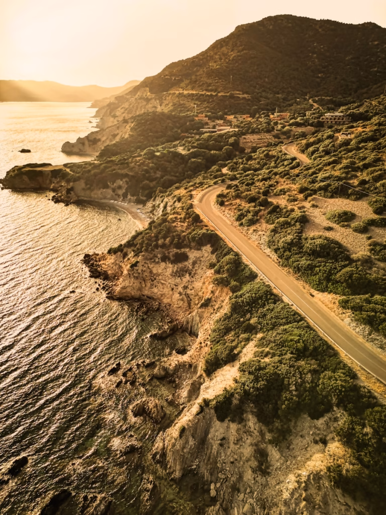 Sardinia Coastal road winds along a sun-drenched hillside.