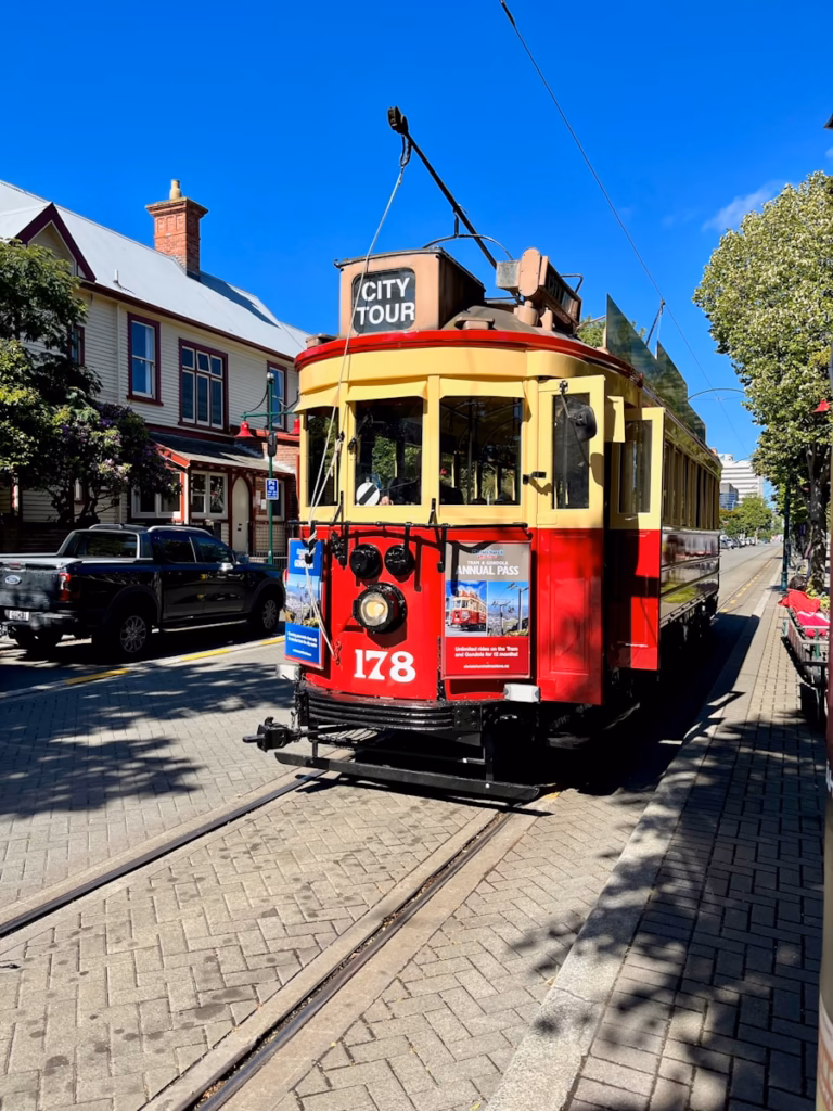 Christchurch a red and yellow trolley car traveling down a street