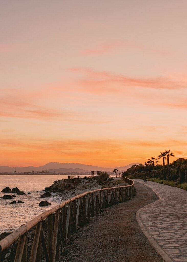 Malaga a person walking down a path next to a body of water