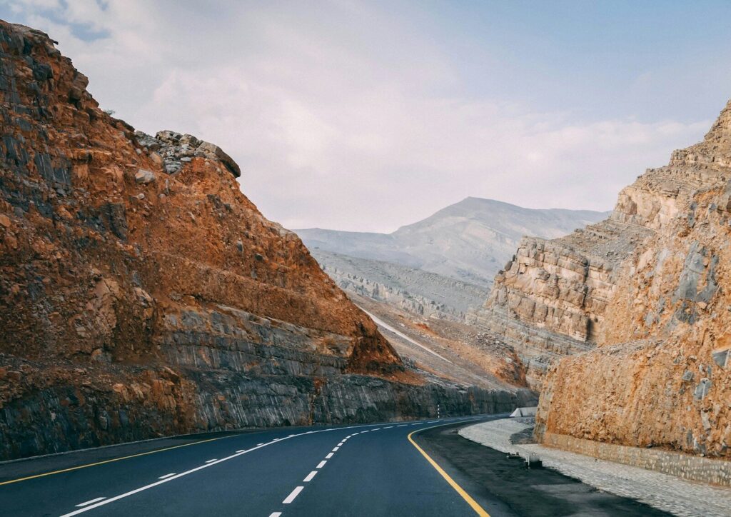 Jebel Jais ashpalted road between brown mountain under blue sky