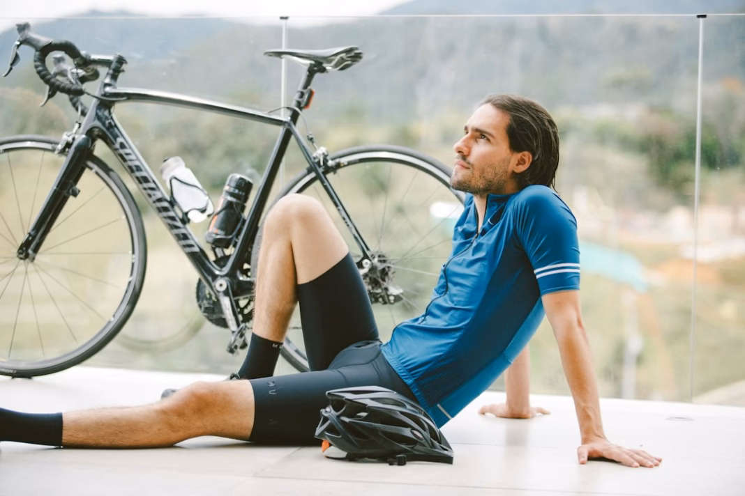 Cyclist sitting beside a road bike after riding