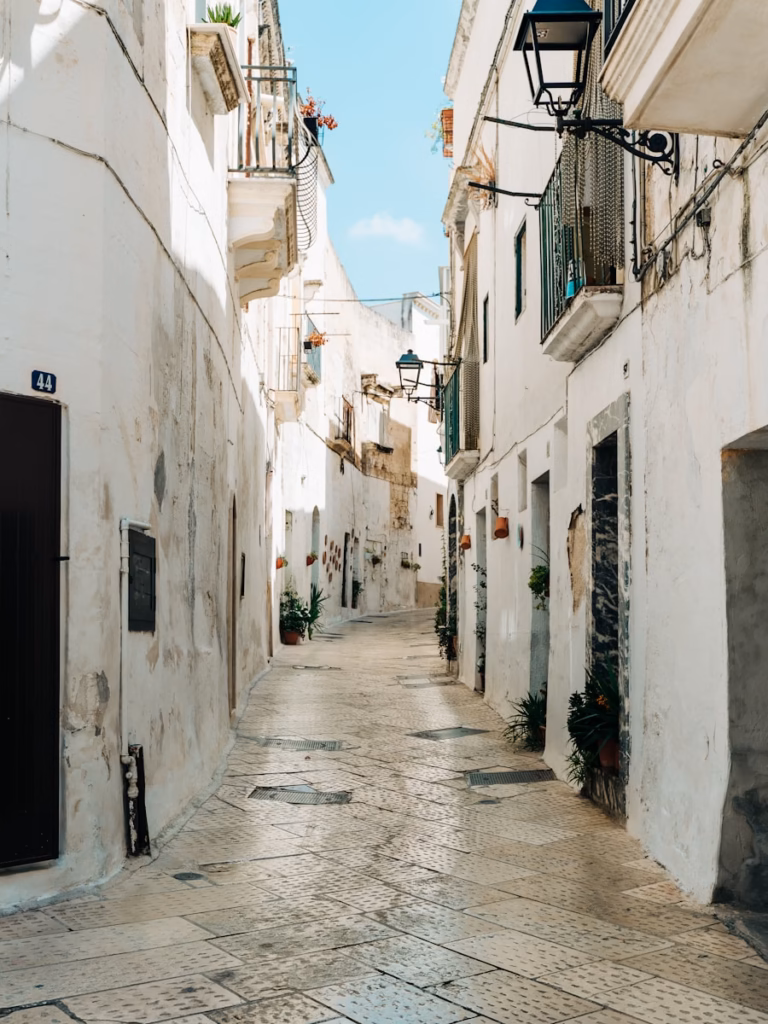 Puglia empty street between white concrete buildings during daytime