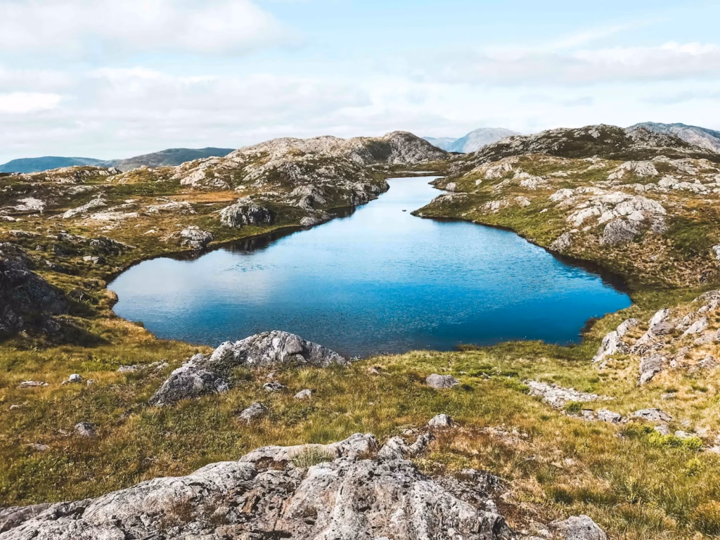 Bergen Norway blue lake surrounded by green grass and gray rocky mountain under white cloudy sky during daytime